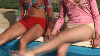 Two attractive women have fun with sex toys by the pool.